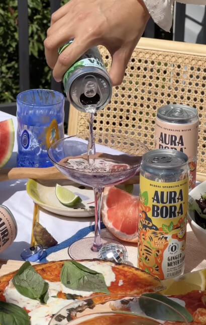 Hand pouring Aura Bora sparkling water into a mocktail glass